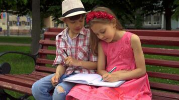 pequeno menina desenha em 1 página do uma caderno enquanto dela amigo esboços em outro video
