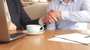 Dynamic business partners shake hands at a cozy cafe video