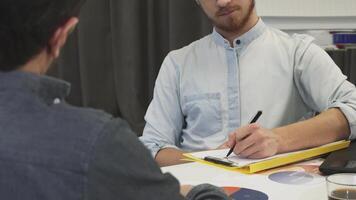 Focused businessman attentively taking notes during a dynamic meeting video