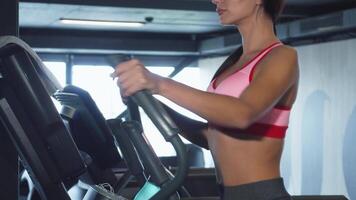Sporty girl exercising on an ellipsoid simulator in a modern gym video