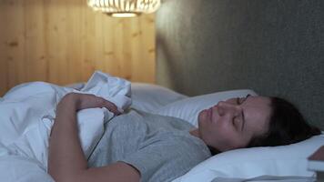 Woman sleeping peacefully, shifting positions in bed during restful night, experiencing deep relaxation within comfortable bedroom environment, embracing serene nighttime tranquility video