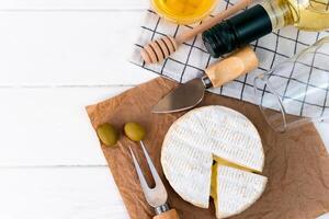 Cheese Camembert, olives, honey and bottle of white wine on the table. Top view. Copy space. photo