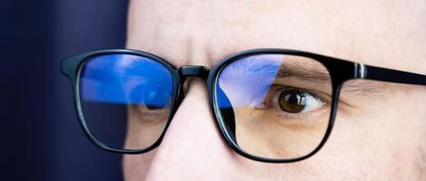 The concentrated look of a young man in glasses looking at the monitor. Work at the computer, work online. Close-up. Place for text. photo