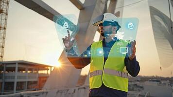 Engineer in safety vest and helmet using virtual reality interface with holographic controls at a bridge construction site during sunset, representing futuristic technology in modern video