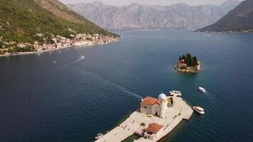 Islands of Our Lady of the Rocks church with the tourist town of Perast in the background. Drone view of the two islands with the town of Perast and the coasts of the Bay of Kotor, Montenegro video