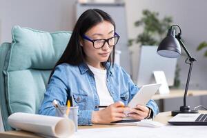Young Asian woman designer working in office using tablet, working on drawing project. photo