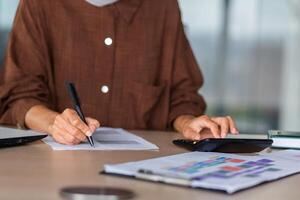 Close-up photo. Female hands of an accountant, auditor, financier, banker working in the office at a table with documents and with a laptop, using a calculator. photo