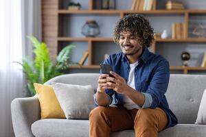 Smiling man using smartphone on couch enjoying a relaxed moment at home photo
