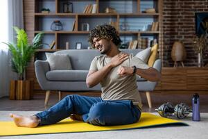 A man was injured while doing fitness and active sports exercises while sitting on the floor in the living room at home, pain in the shoulder joint photo