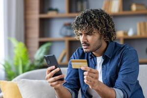 Man confused while using phone for online banking with credit card photo