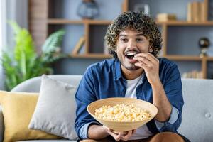 Man enjoying a bowl of popcorn while relaxing on the sofa at home photo