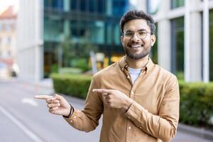 Smiling man pointing in opposite directions outside modern office buildings photo