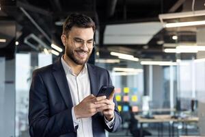 Smiling businessman using smartphone in modern office environment photo