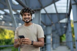 Young man with headphones using a smartphone during a break from his fitness routine on a covered walkway. Active and technology-driven lifestyle. photo