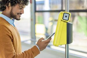 Young man uses his smartphone to scan the ticket on a train, ensuring a smooth and modern commute. Focus on the scanner. photo