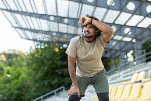 Tired athlete resting after active physical exercise and running, man breathing and relaxing. photo