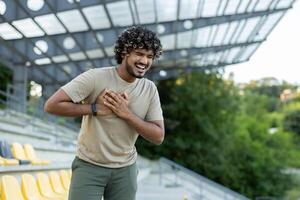 Man suffering from chest pain heart attack during active physical training. Athlete holding hands on chest while jogging. photo
