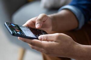 Close up of dark skinned hands holding and using a smartphone device to browse social media, connect, or play a game. photo