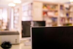 Blurred background of traditional library with computer monitor on a foreground and bookshelfs photo