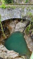 Serene natural pool Orrido di Bellano surrounded by rocky cliffs and lush greenery under a stone bridge showcasing tranquil water and vibrant nature scene photo