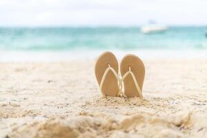 Flip flops resting on the warm sandy beach as the calm turquoise ocean stretches into the distance photo
