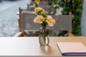 Elegant table setting in charming outdoor cafe with fresh flowers and a notebook photo