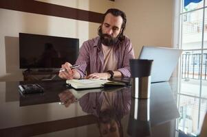 Man Working at Home Desk with Notebook and Laptop in Bright Apartment photo