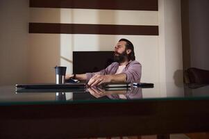 Bearded Man Working at Home Office Desk With Relaxed Expression photo