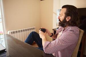 Man Sitting Relaxed at Desk Drinking Coffee in a Modern Home Office photo