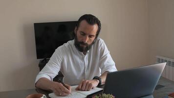 Focused Man Working Diligently at Desk with Laptop and Notebook photo