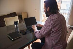 Man Working on Laptop at Home with Notebook and Mug photo