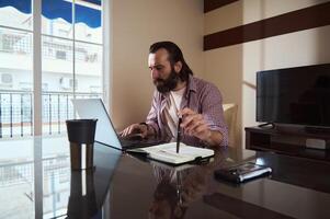Freelancer Working on Business Project at Home with Laptop and Notepad photo