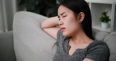 Handheld high angle view shot, Stressed young woman sits alone on a sofa, thinking aimlessly, feeling worried about something. Life problems video