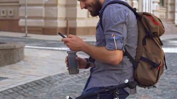 Caucasian cyclist refreshes with water while checking his smartphone video
