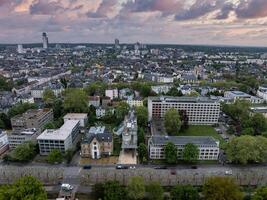 Aerial image of Frankfurt, Germany, showing mid sized buildings, greenery, and a dense urban area with a distinctive high rise under a cloudy sky. photo