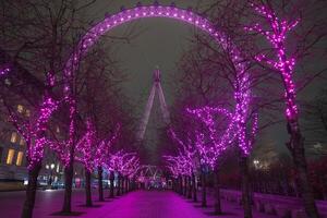 The London Eye is illuminated against the night sky, framed by a pathway of trees adorned with vibrant pink lights in a symmetrical arrangement. photo