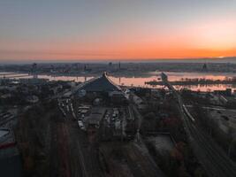 Serene sunrise over Riga, Latvia, featuring the Daugava River, National Library, historic spires, and railway tracks blending modern and historic elements. photo