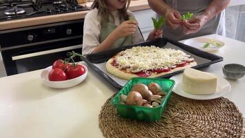 Chef and child adding basil leaves to pizza video