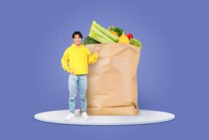 A customer stands joyfully next to a massive paper grocery bag overflowing with colorful vegetables and fruits. Shopping for fresh produce has become a staple of daily life. photo