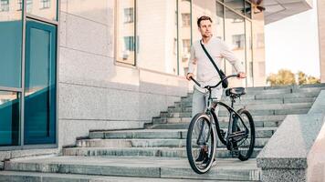 A young man navigates a set of stairs with his bike in an urban setting. Dressed casually, he shows confidence as he embraces a relaxed lifestyle while enjoying the moment outdoors. photo