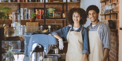 Meeting and waiting for clients in modern cafe after lockdown. Smiling millennial african american guy and lady in aprons and gloves with espresso machine and equipment in morning in cafeteria photo