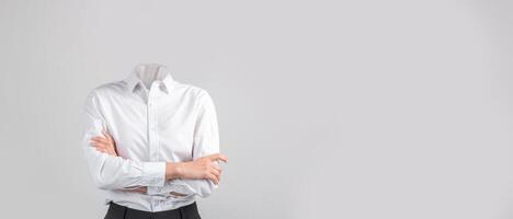 A headless figure dressed in a white shirt and dark pants stands with arms crossed in front of a plain background. This evokes a sense of isolation and unique lifestyle expression without a head. photo