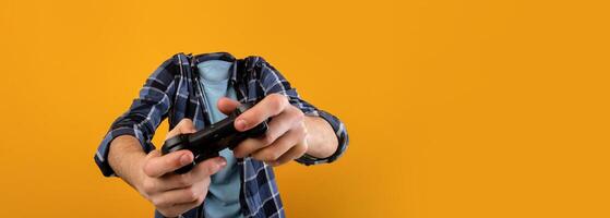 Two hands grip a game controller, lost in the virtual world, as a vibrant yellow backdrop enhances the mood of leisure and entertainment without showing any facial details. photo