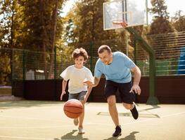 Portrait in action of father and son playing basketball on court together, man leading the ball photo