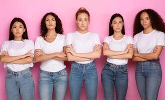 Discontented Multiracial Female Group. Five Displeased Multiethnic Ladies Standing Crossing Hands Disapproving Something Posing Over Pink Studio Background, Looking At Camera photo