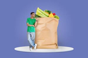 A shopper stands beside a large paper bag filled with fresh groceries. These items symbolize the new normal of shopping and delivery while maintaining social distance. photo
