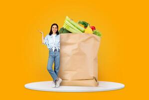 A customer stands next to a large paper bag filled with fresh produce. The vibrant background highlights the new normal of grocery shopping and delivery in today's world. photo