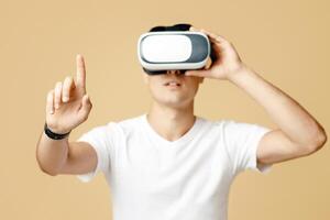 Man in vr glasses playing games with virtual reality headset trying to touch something with finger. Surprised young man student in white t-shirt use blank space, isolated on light background photo