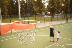Scoring Goal. Man throwing ball, playing basketball with his son, selective focus on hoop, blurred background photo