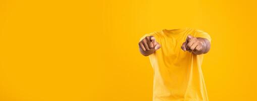 Headless individual is seen pointing toward the viewer against a bright yellow background. This isolated lifestyle portrayal emphasizes blank space and brings a unique perspective. photo